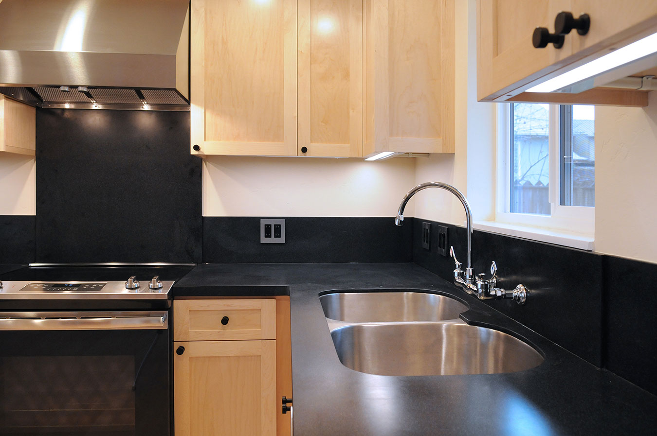 custom kitchen design with light wood cabinets and black counters